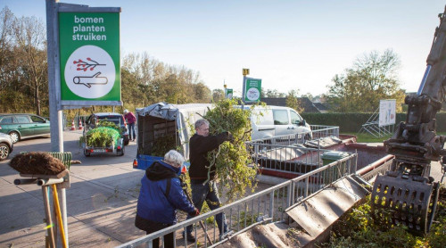 twee mensen doen snoeiafval in de bak bij het afvalbrengstation