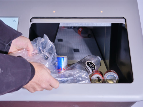 Zak met plastic statiegeldflesjes en -blikjes wordt in de bulkmachine geleegd