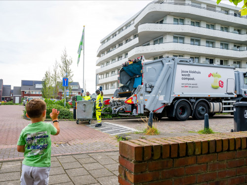 HVC chauffeurs zwaaien naar jongen tijdens inzamelen papier